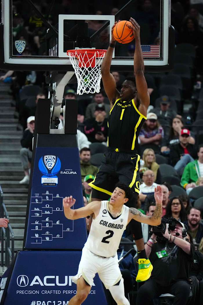 Oregon Ducks center N'Faly flies over a Colorado Buffaloes defender for a dunk in the 2024 Pac-12 Tournament.